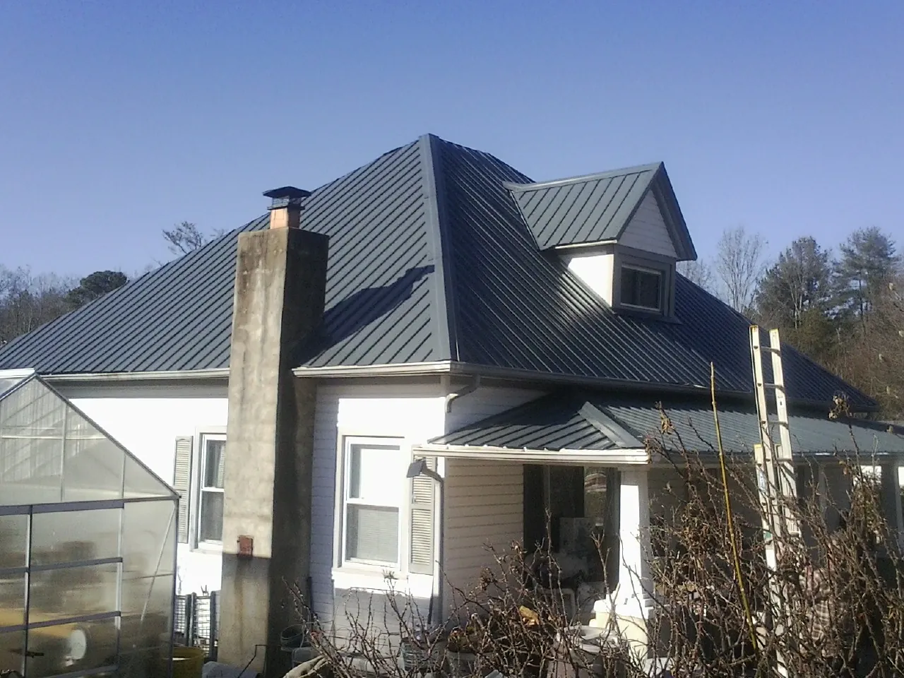 Dark blue standing seam metal roof on a white farmhouse with dormer — Slate & Tile Roof Repair by Roofing Brothers in Canyon Dam