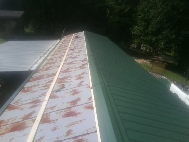Old rusted panels beside newly installed green metal roofing — Wind Damage Roof Repair by Roofing Brothers in Canyon Dam