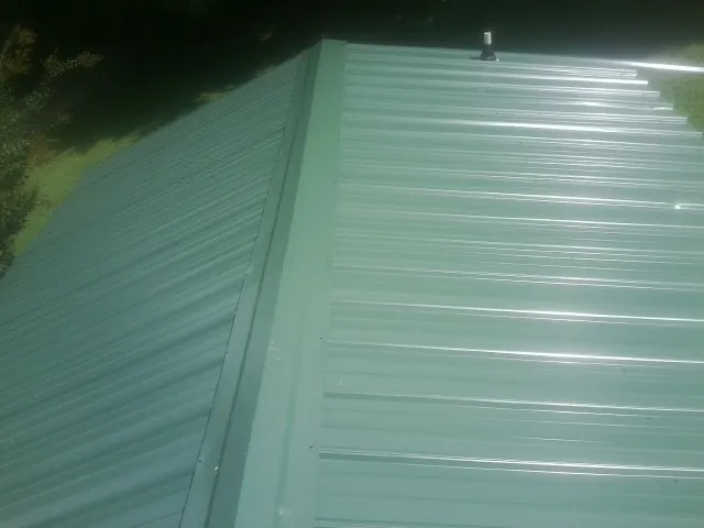 New green metal panels meeting at the ridge of a roof — Flat Roof Repair work by our crew in Canyon Dam