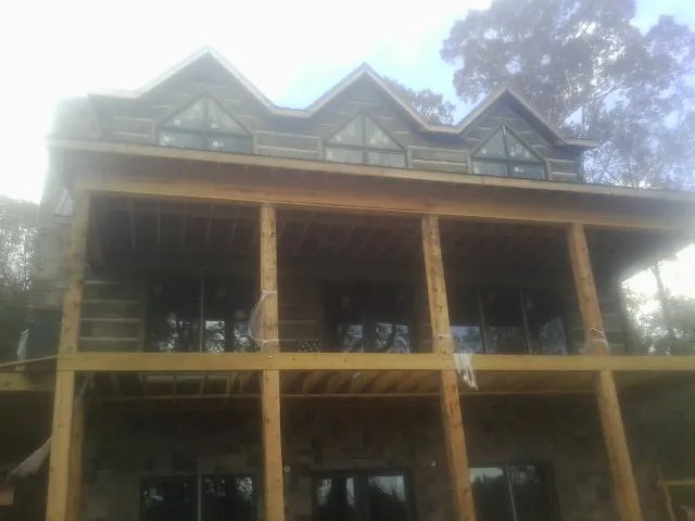 Dormers and porch framing on a large log home under construction — Roof Coating work by our crew in Canyon Dam