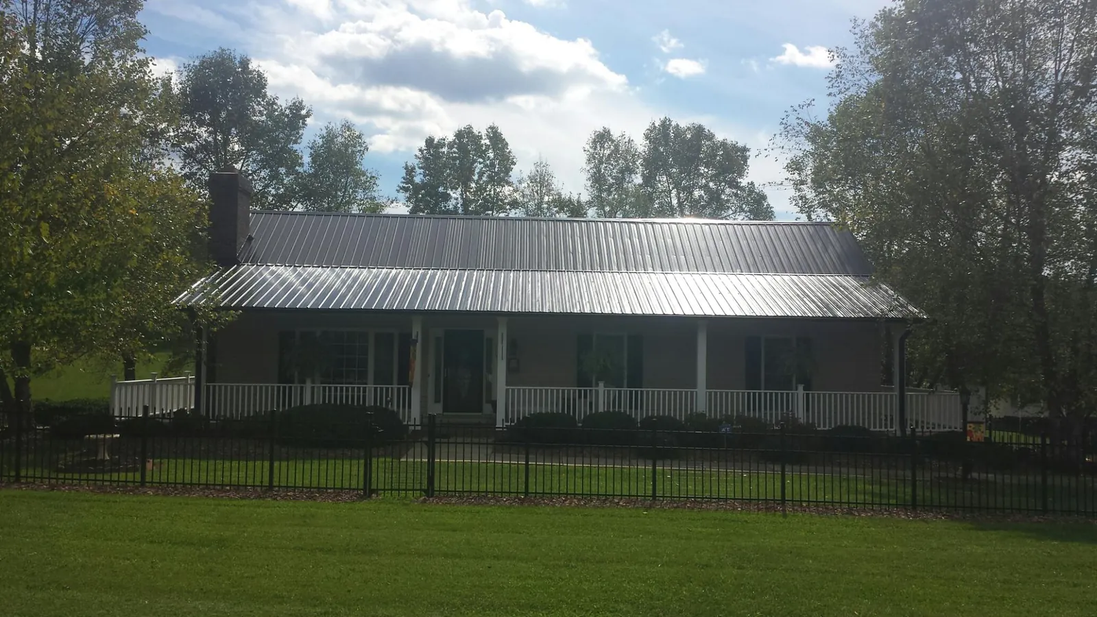 Gray metal roof on a brick ranch with a full width front porch — Gutter Guard Installation work by our crew in Canyon Dam