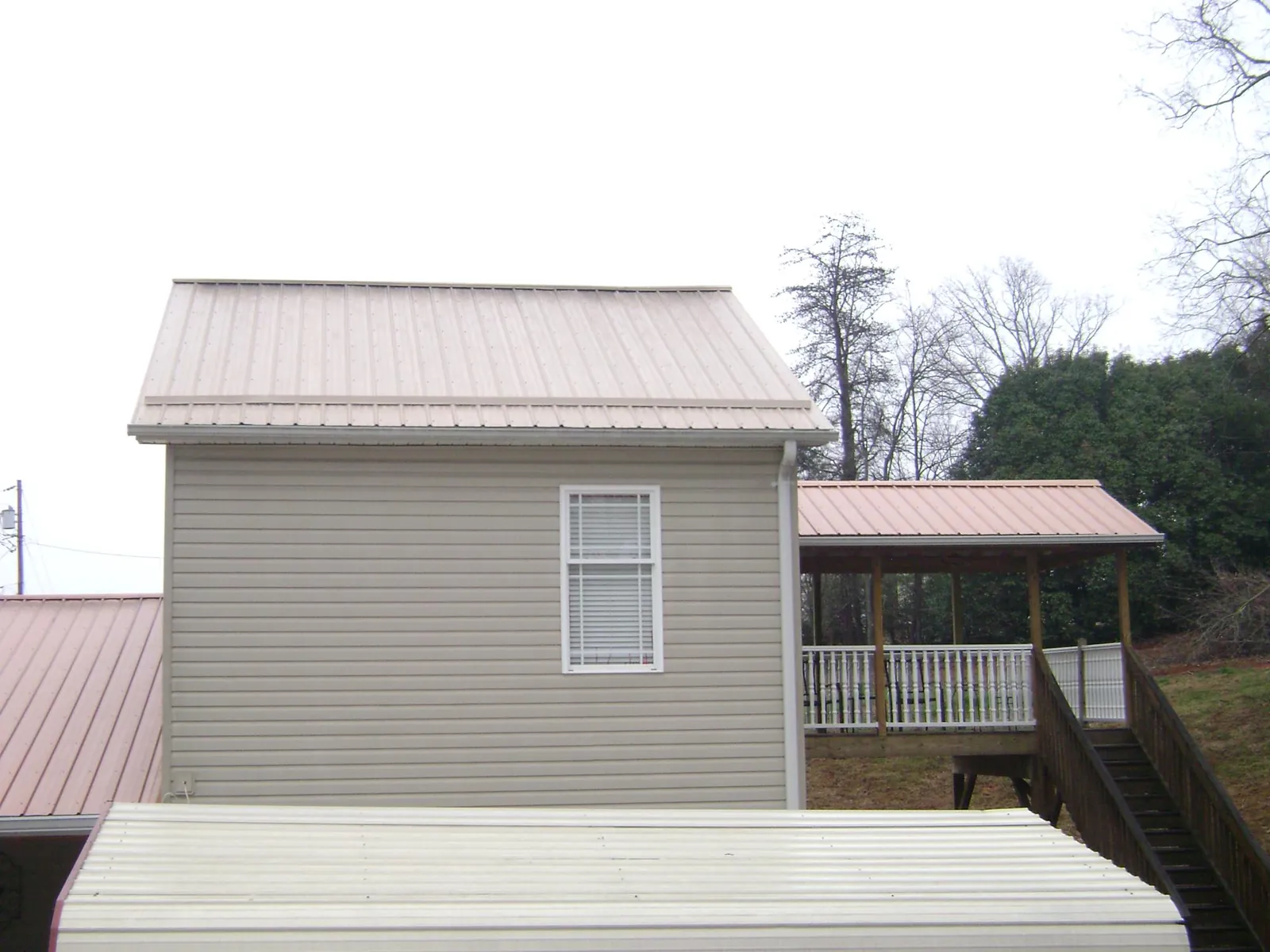 Tan metal roofs on a two story addition and attached porch, from a Roof Replacement job in Canyon Dam
