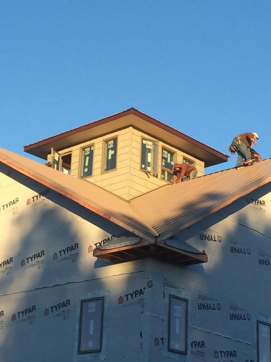 Roofers working around a rooftop cupola on a new metal roof at sunset — Roof Waterproofing in Canyon Dam by Roofing Brothers